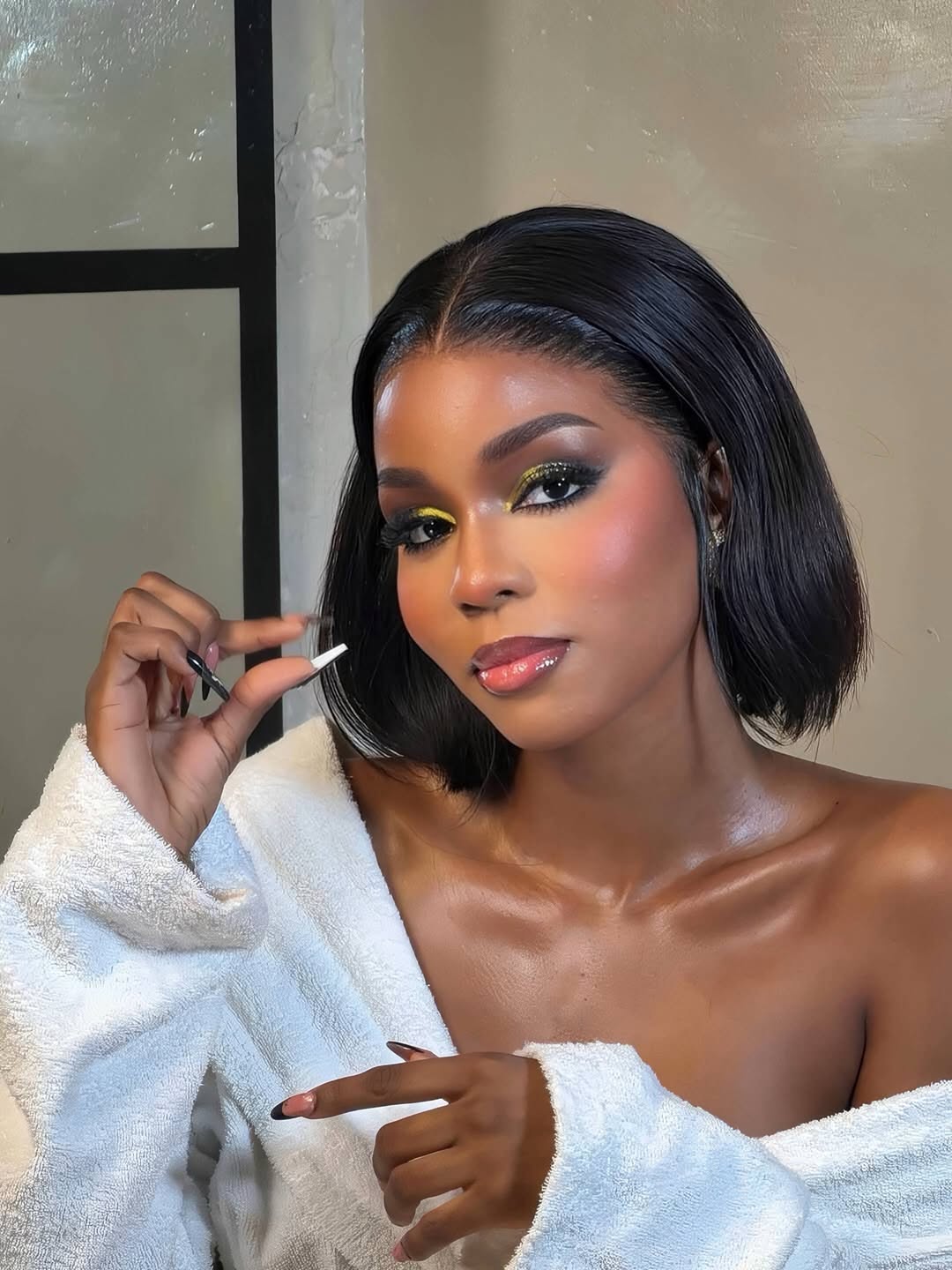 Angel with a sleek bob, gold glitter eye makeup and a white robe